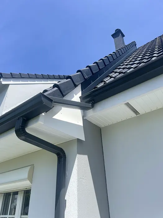 Gouttière anthracite, rive et faîtage sur maison blanche